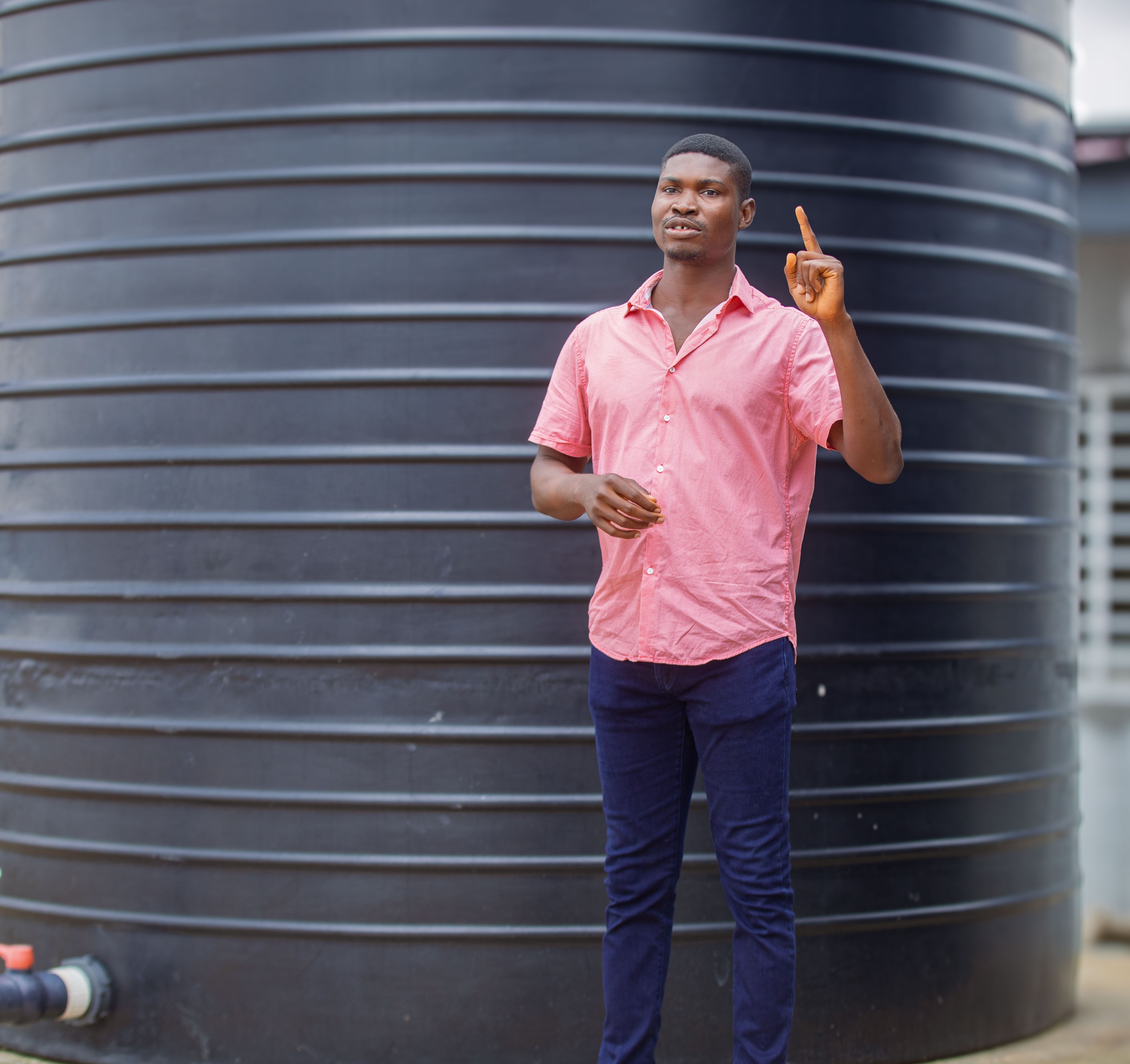 Alex Afari pointing at one of the 20,000 litre capacity water tank.
